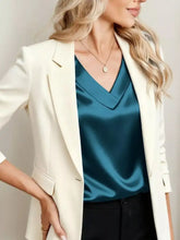 Cream-colored blazer with sleek tailored fit and subtle sheen paired with satin v-neck cap sleeve blouse