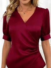 A sleek deep burgundy satin v neck wrap blouse with puffed short sleeves and flattering neckline detail