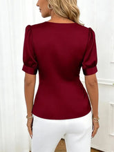 A deep red satin v neck wrap blouse with puffed short sleeves and a fitted silhouette