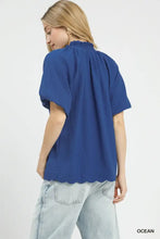 Blue short-sleeved scalloped hem textured blouse with ruffled neckline in lightweight fabric for stylish wear