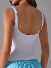 White scoop neck active tank with ribbed fabric, thin straps, open back, and detachable chest pads
