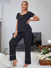 Black scoop neck top and elastic waist pants lounge set with short sleeve length and white piping on pant cuffs