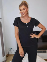 Black scoop neck top with short sleeve length and three white button details in lounge set with elastic waist pants