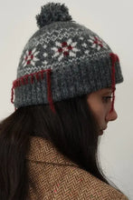 Gray geometric knit hat with seam trim, pompom, and red-white snowflakes