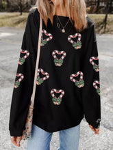 Black corduroy sweater with festive red and white candy cane heart appliqués and green bow details care instructions included
