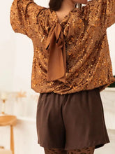 Back view of a shimmering gold sequined blouse with a brown satin tie-back bow in sequin embellished tie-back blouse design