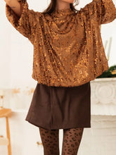 A shimmering gold sequined blouse with high neckline and voluminous sleeves featuring a tie-back detail