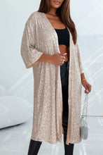 Gold sequined kimono cardigan with varying sleeve lengths, black bralette, leggings, silver purse
