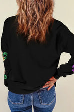 Woman in sequin round neck dropped shoulder sweatshirt with colorful sleeves and blue jeans