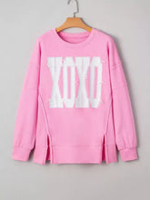 Pink long-sleeved sequin xoxo letter graphic sweatshirt with side slits and slightly stretchy fabric with care instructions