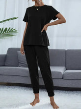 Black shiny round neck short sleeve top with relaxed fit side pockets highlighting sleeve length and comfort