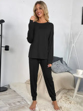 Black long-sleeved shiny round neck top and drawstring pants lounge set with relaxed fit and elastic cuffs