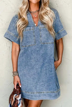 A light blue denim mini dress with short sleeves, collar, and two front patched pockets