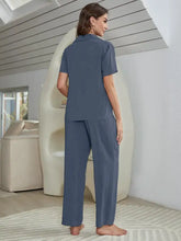 A woman wearing a navy blue short sleeve lounge set with a collared shirt bralette and wide-leg pants