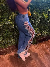 High-waisted blue denim distressed jeans with a bold side slit, frayed edges, and visible stitching detail