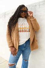 Woman in brown coat, Simply Love full size Gobble short sleeve graphic tee, ripped jeans