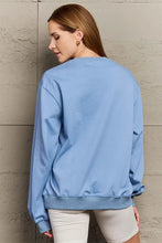 Light blue graphic dropped shoulder sweatshirt with long sleeve length over off-white biker shorts