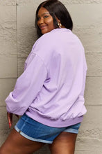 Dark-skinned woman in lavender long-sleeve Happy Halloween graphic sweatshirt
