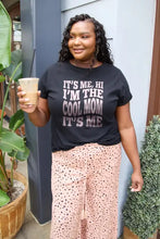 Woman in Simply Love black basic style round neck t-shirt and patterned wide-leg pants holding a drink