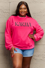 Plus-size woman in Simply Love full-size KARMA graphic long-sleeved sweatshirt and cuffed denim shorts