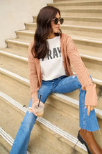 Woman in peach cardigan over full size pray round neck t-shirt, blue jeans, boots with iced coffee