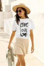Woman in Simply Love full size love short sleeve t-shirt, beige skirt, straw hat