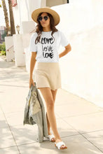 Woman in love short sleeve t-shirt, beige skirt, white sandals, holding denim jacket