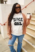 Woman in Spice Girl short sleeve t-shirt, rust cardigan, ripped jeans