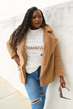 Woman in tan teddy bear coat over Simply Love Thankful short sleeve t-shirt and jeans