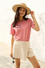 Simply Love pink short sleeve Spoiler God Wins graphic t-shirt with beige skort and wide-brim hat