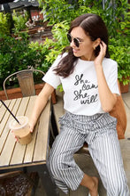 Woman in Simply Love short sleeve white t-shirt and striped pants holding iced coffee
