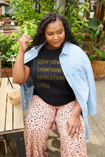 Black plus size t-shirt with gold champagne resolutions text, layered under simply love denim jacket