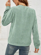 Woman in skull graphic dropped shoulder sweatshirt with mint green corduroy top and jeans