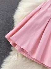 A soft pink pleated skirt paired with a sleeveless belted denim dress featuring lightweight fabric and a neatly stitched hem