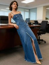 A long medium-wash blue denim dress with thin straps front button closure and sleeveless frayed hem detail
