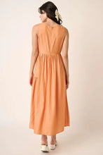 Peach sleeveless midi dress with ruched waist and floral hair accessory
