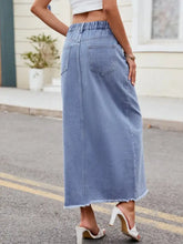 Light blue denim skirt with slit asymmetrical waist, high-waisted elastic band, and frayed hem in maxi length