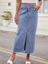 A light blue denim skirt featuring a slit asymmetrical waist with a front slit and frayed hem design