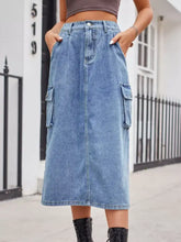 A mid-thigh length faded blue slit buttoned denim skirt with large cargo pockets and button closure