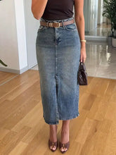 Mid-thigh length slightly stretchy denim skirt with slit front, faded blue wash, classic cut, and frayed hem care instructions included