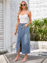 A light-wash slit midi denim skirt with pockets and high waist stretch waistband in soft denim material
