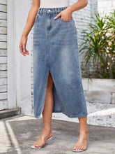 A mid-blue slit midi denim skirt with button closure featuring waist stretch and functional pockets