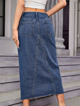 Mid-rise midi denim skirt with classic faded blue wash frayed hem slit and functional pockets in denim fabric