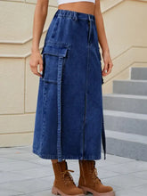 A mid-thigh length high waist denim skirt with elastic waistband, front zipper, and large side cargo pockets