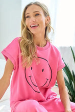 Woman in smile face drop shoulder pink sweatshirt and sweatpants set