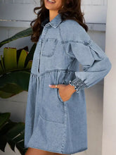 Light blue denim dress with smocked cuffs, collar, long sleeves, and two front pockets in a denim shirt style