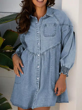 Light blue denim dress with button front, smocked cuffs, and gathered waist in a flared denim shirt mini dress style