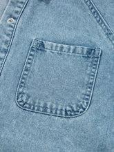 Light blue denim shirt pocket with reinforced stitching and silver button on smocked cuffs flared denim dress
