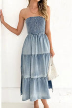 A denim blue smocked tube slit tiered denim dress with a strapless maxi design and subtle fading