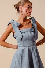 Light blue denim dress with square neckline and tied shoulder bow ribbons featuring a diamond bow design